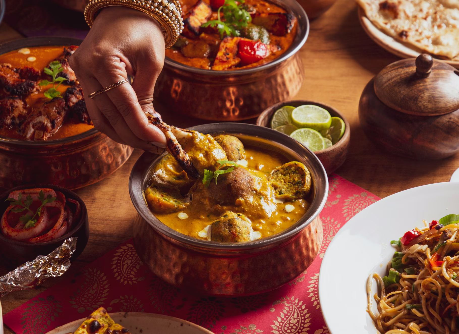 Indická kari, tandoori a čerstvý naan na prostřeném stole, fotografie, avif