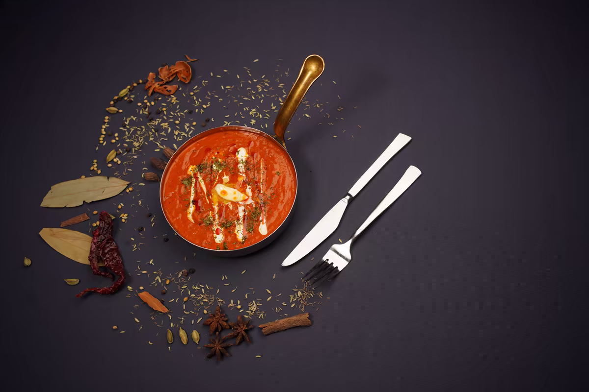 Butter chicken v měděné pánvi s kořením na tmavém pozadí, fotografie, avif
