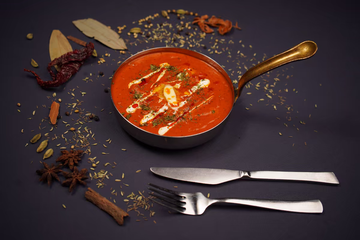Butter chicken s celým kořením rozsypaným kolem pánve, fotografie, avif