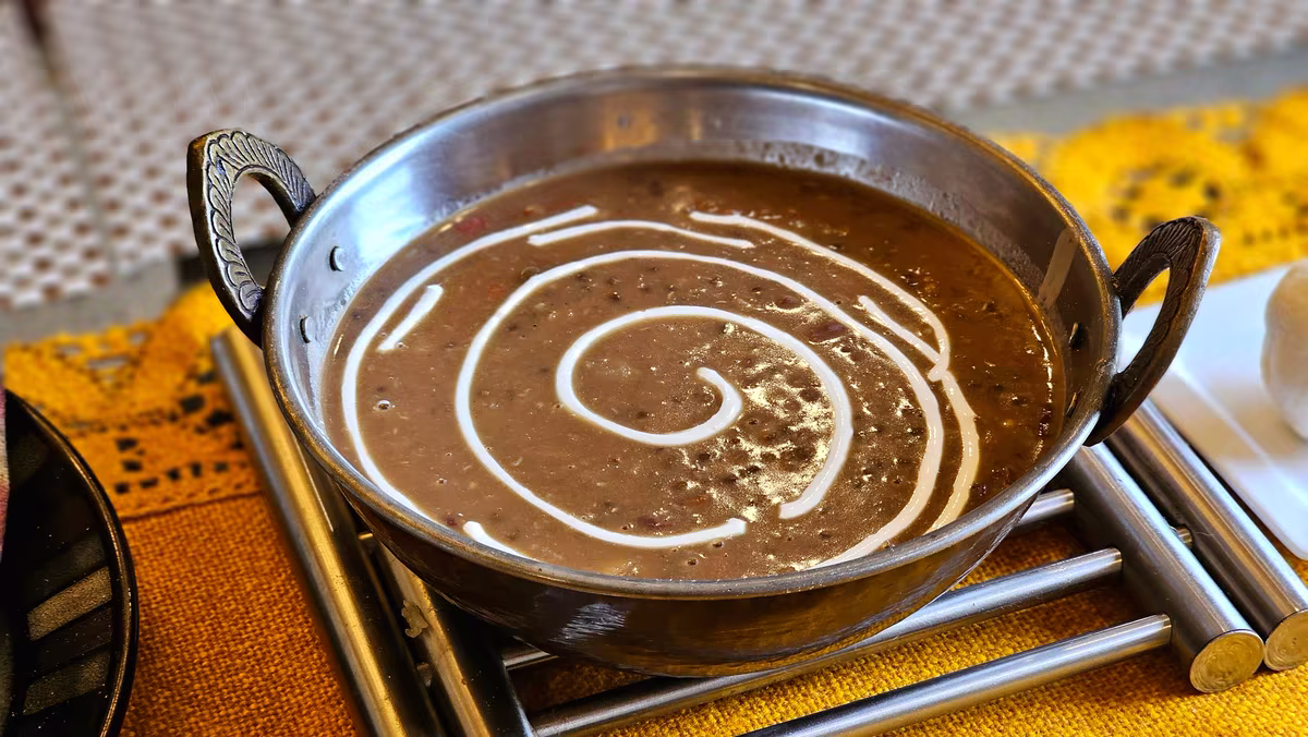 Tmavá dal makhani v ocelové pánvi se smetanovou spirálou, fotografie, avif