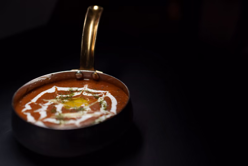 Dal makhani v tmavé pánvi se smetanovou spirálou a máslem, fotografie, avif