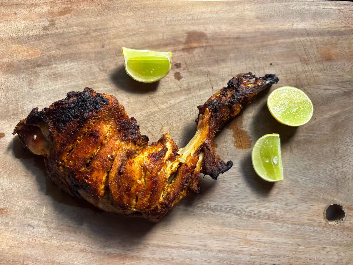 Opečené tandoori kuřecí stehno s limetkou na dřevěném prkénku, fotografie, avif